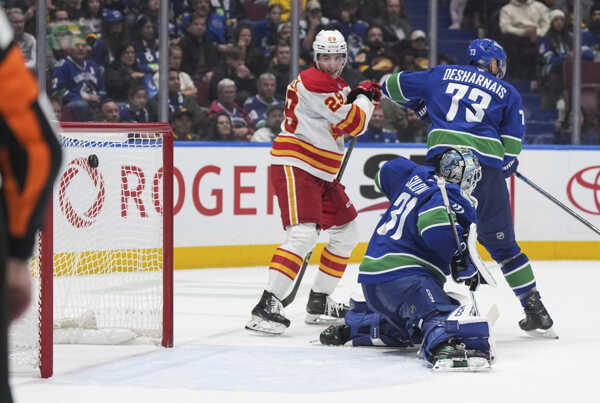 Zľava slovenský útočník Calgary Samuel Honzek, brankár Canucks Arturs Silovs a jeho spoluhráč Vincent Desharnais.